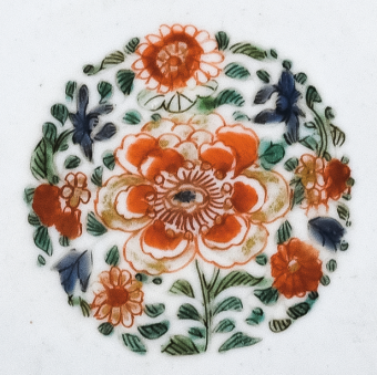 圖為清代五彩花卉紋碟細節(jié)圖，碟心主題紋飾為團花圖，紅花綠葉，相映成趣。（來源：廣州十三行博物館）