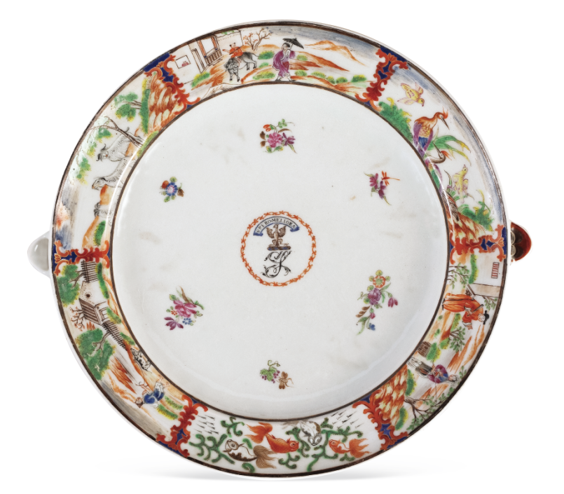 圖為清嘉慶廣彩描金花卉人物紋章溫盤，盤沿兩側(cè)對稱置半圓形注水口。外邊飾為鄉(xiāng)村風(fēng)景紋，盤心繪紋章，四周繪六組折枝花卉圍繞。溫盤又稱暖盤，使用時將熱水由孔注入，使盛入淺盤的食物保溫，達(dá)到防冷溫?zé)岬男Ч?。（來源：廣州十三行博物館）
